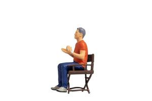 Miniature people sitting on chair isolated on white background photo