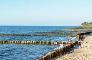 A breakwater made of logs cuts through the sea wave photo