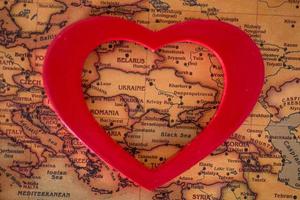 heart with national flag of ukraine on a vintage world map crack paper background. photo
