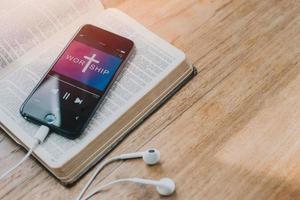 Smartphone over the holy bible on wooden background, Worship to God. vintage color. copy space. christian background, Online church from home concept. photo