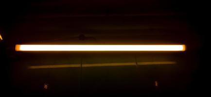 Detail of a fluorescent tube mounted on a wall, false yellow color light. photo