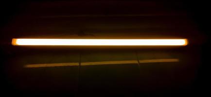 Detail of a fluorescent tube mounted on a wall, false yellow color light. photo
