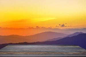 mesa de madera y desenfoque de belleza, cielo al atardecer y montañas como fondo. foto