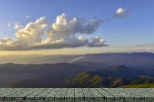 Wooden table and blur of beauty, sunset sky, and mountains as background. photo