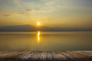 mesa de madera vacía en la hermosa puesta de sol del lago foto