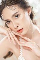 hermosa mujer asiática joven con piel limpia y fresca con perlas sobre fondo brillante. cuidado facial, tratamiento facial, belleza y spa, lindo retrato de mujeres asiáticas. foto