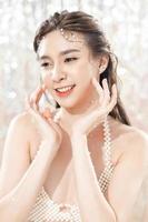 Beautiful young asian woman with clean fresh skin with pearls on glitter background. Face care, Facial treatment, beauty and spa, Cute Asian women portrait. photo