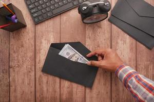 person hand putting cash in a envelope. top view photo