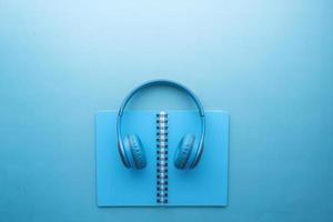 Audio book concept. Headphones and notepad on white background photo