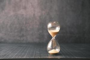 hourglass on table, sand flowing through the bulb of sandglass photo