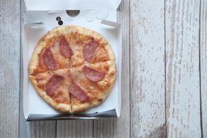 Slice of cheese pizza on a takeaway packet on table photo