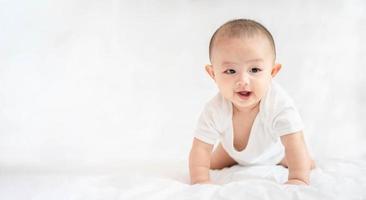 Happy family, Cute Asian newborn baby boy lying play on white bed look at camera with laughing smile happy face. Little innocent new infant adorable child in first day of life. Mother's Day concept. photo
