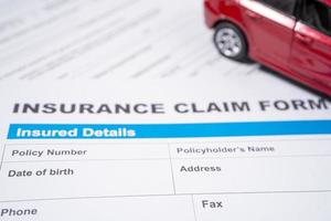 Coche rojo en el formulario de accidente de reclamación de seguro, concepto de préstamo de coche, seguro y tiempo de arrendamiento. foto