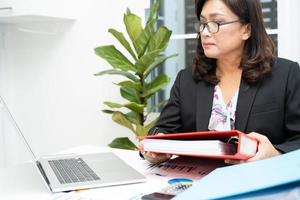 Asian accountant working and analyzing financial reports project accounting with chart graph and laptop in modern office, finance and business concept. photo