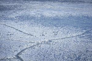 Snowy ice surface with cracks in blue shades and vignette photo