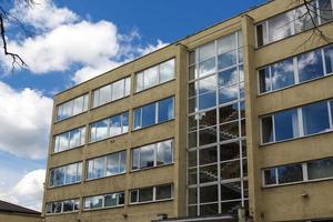 Sky and clouds reflected in yellow concrete building windows with visible staircase photo