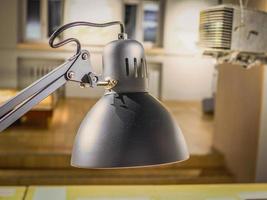 Black lamp dusty metal hood hanging over table on office background photo