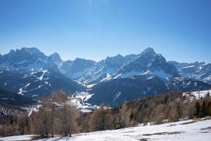 Scenic view of snow covered mountain range and forest against clear blue sky photo