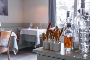 Close-up of dried flowers decorated in bottles by glassware on table at hotel photo