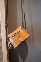 Close-up of yellow leather bag hanging against wall in empty hotel room photo