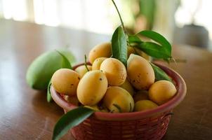 Marian Plum in a basket - Thailand agriculture, Asian tropical fruits display on the table with blur background and selective focus. Copy space. photo