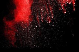 nube de explosión de polvo rojo sobre fondo negro. congelar el movimiento de salpicaduras de partículas de polvo de color rojo. foto