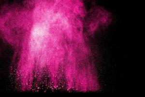 Pink color powder explosion on black background. Launched colorful dust particles splashing. photo