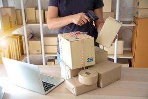 caja de cartón de escaneo de mensajería con escáner de código de barras en el almacén. primer plano de las cajas de escaneo manual del gerente del almacén con lector de código de barras foto