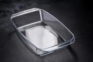 A rectangular glass empty dish for baking on a dark concrete background photo