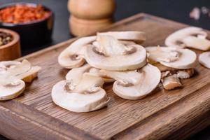 Beautiful young white champignons torn to slices on a dark concrete background photo