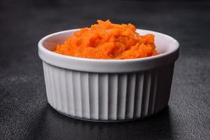 Pumpkin carrot baby puree in bowl on a dark background photo
