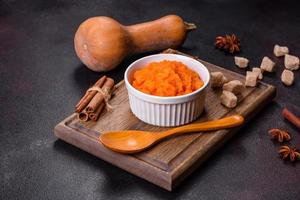 Pumpkin carrot baby puree in bowl on a dark background photo