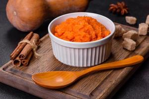 Pumpkin carrot baby puree in bowl on a dark background photo