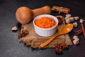 Pumpkin carrot baby puree in bowl on a dark background photo