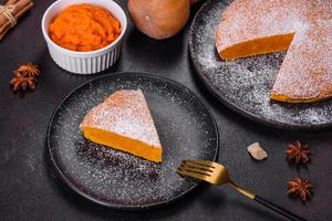 Pumpkin pie, tart made for Thanksgiving day with whipped cream on a black plate photo