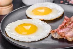 English breakfast with fried eggs, bacon, beans, tomatoes, spices and herbs photo