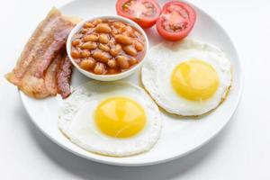 English breakfast with fried eggs, bacon, beans, tomatoes, spices and herbs photo