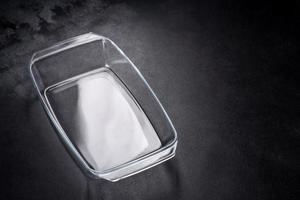 A rectangular glass empty dish for baking on a dark concrete background photo