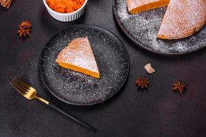 Pumpkin pie, tart made for Thanksgiving day with whipped cream on a black plate photo