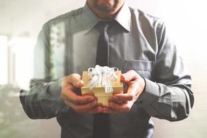 gift giving,businessman hand holding a gift box in a gesture of giving front view,filter effect photo