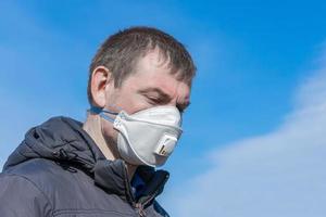 A pale and sick person infected with an infection or virus in a medical mask with a sad face photo