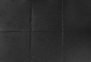 Black crumpled unfolded paper sheet texture background. Paper folded in six. Full frame photo