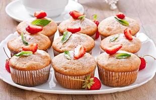 Strawberry muffin on a white plate with a fresh strawberry
