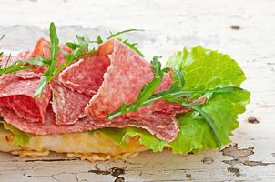 Sandwich with salami, lettuce, tomato and arugula photo