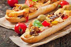 Big sandwich with roasted vegetables  and chicken with cheese and basil on old wooden background photo