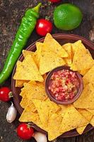 chips de nacho mexicanos y salsa en un tazón sobre fondo de madera foto