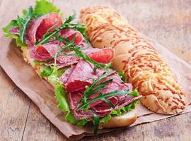 Sandwich with salami, lettuce, tomato and arugula photo