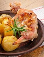 Oven Baked rabbit legs with potatoes and rosemary photo