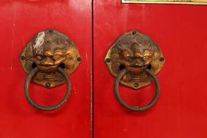 Brass door knobs are on red door and shape tiger head, the door knobs are design chinese style in shrine, Thailand photo