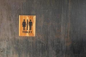 Toilet of man and woman sign on black wall. photo